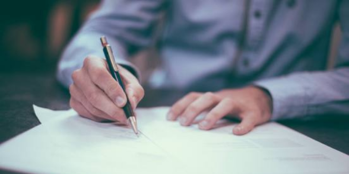 Imagen de una persona escribiendo en un papel