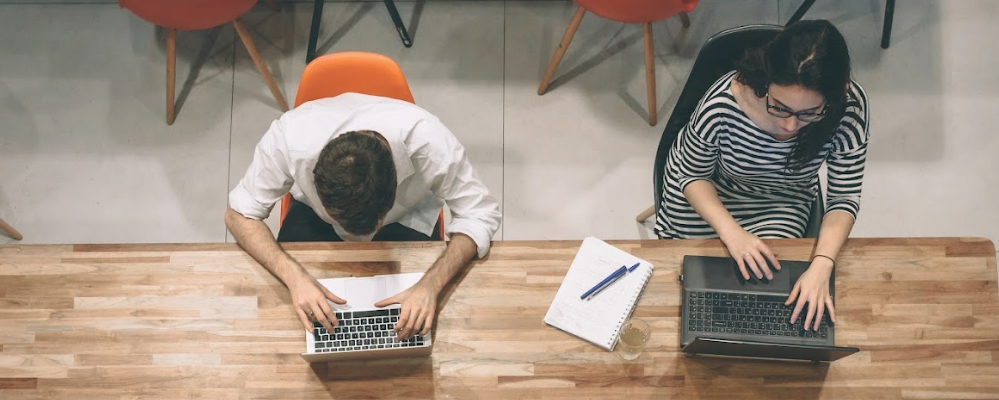 2 estudiantes sentados con un portátiles en la mesa