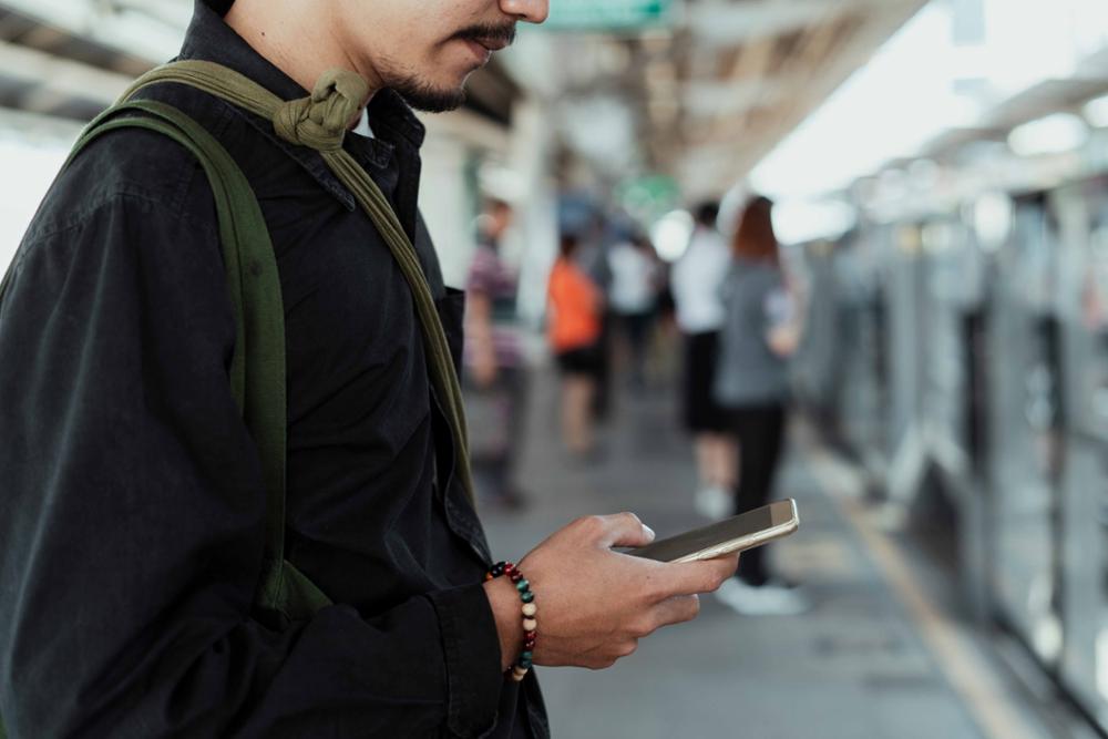 Un joven consulta el móvil en una estación de tren