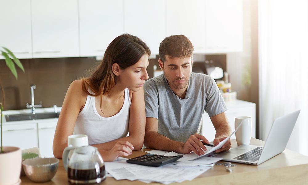 Dos jóvenes consultando un ordenador y datos financieros