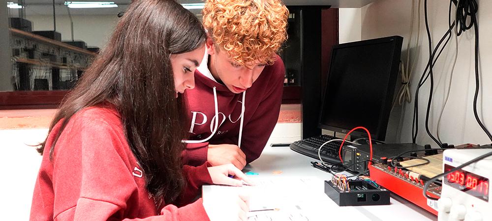 Chico y chica adolescentes delante de un circuito electrónico
