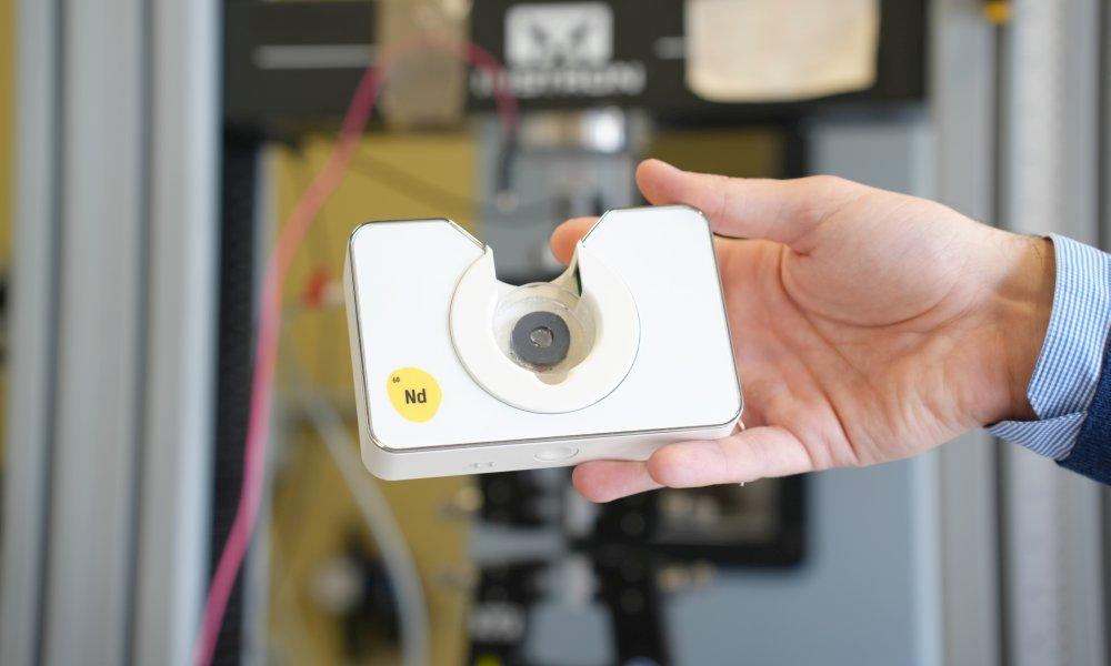 Fotografía de Neomag, un dispositivo portátil, creado por 60Nd, con tecnología basada en materiales magneto inteligentes. Es rectangular, blanco y cabe en la palma de una mano. Crédito: UC3M.