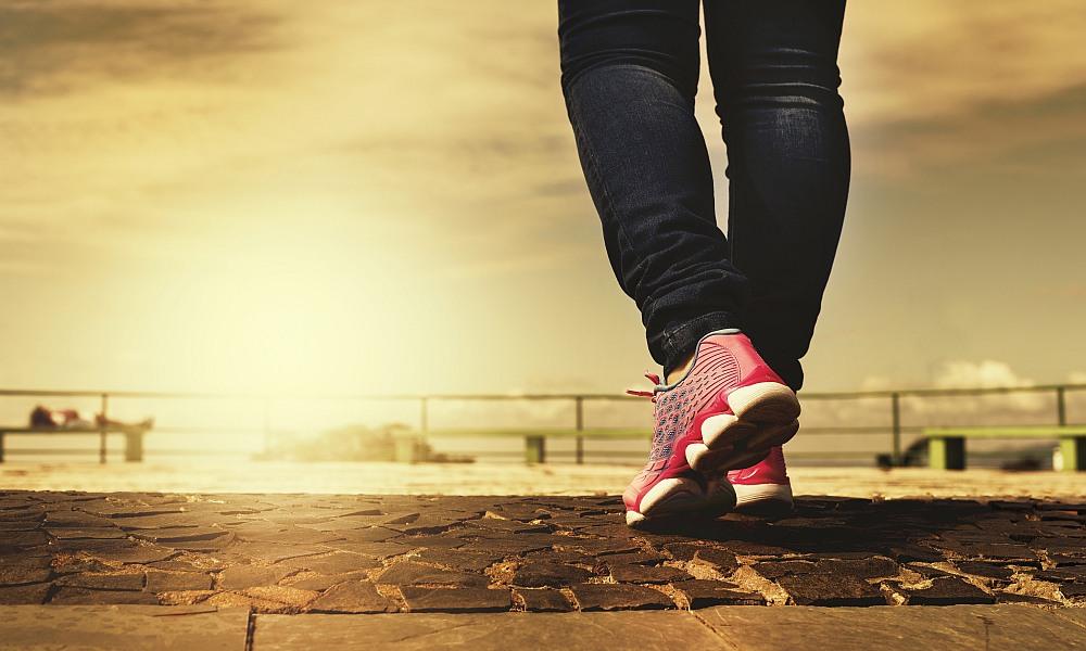 Primer plano de unas piernas caminando en un paseo marítimo. Imagen de Daniel Reche en Pixabay